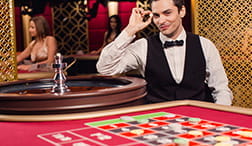 A dealer leaning on an Evolution roulette table.